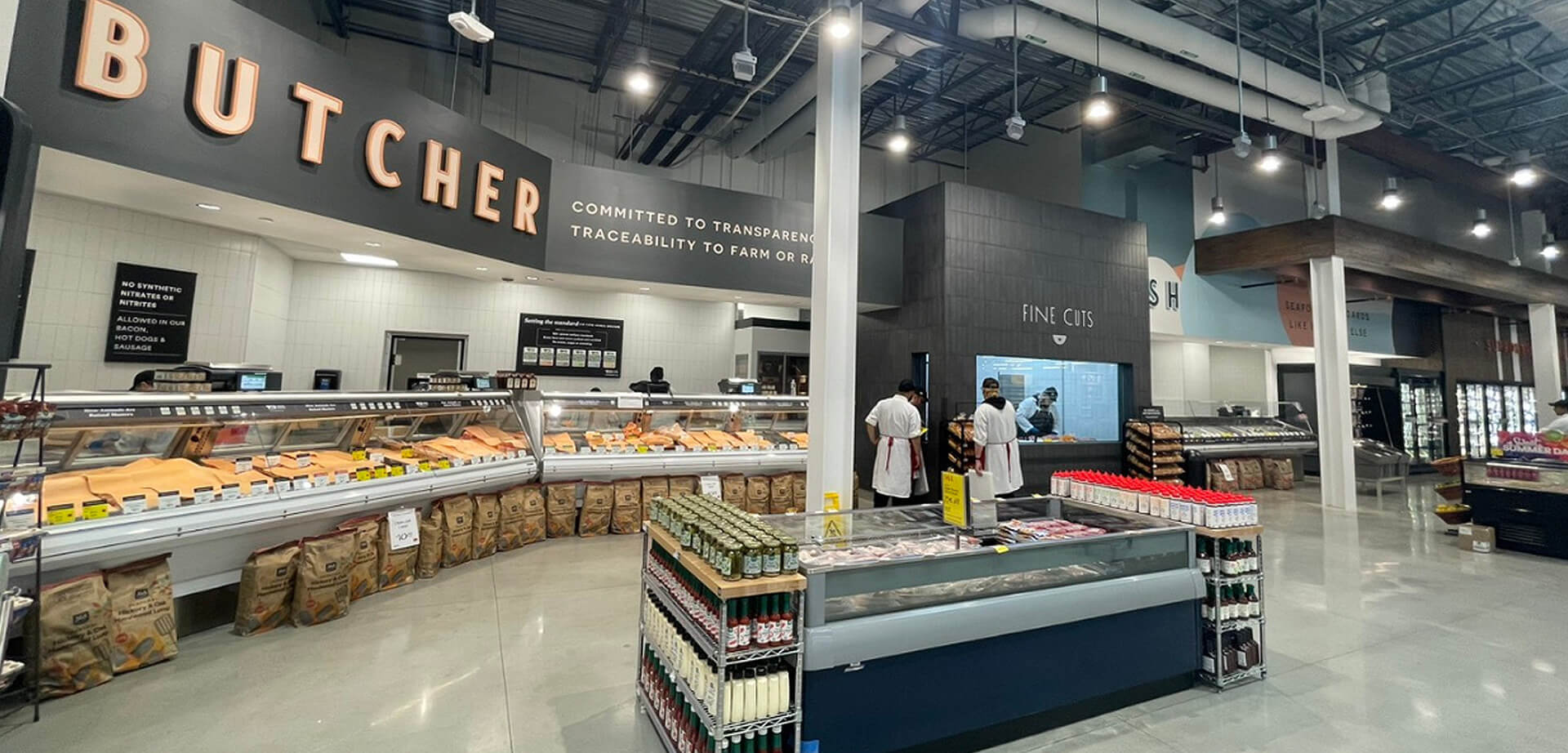 Whole Foods Market grocery store, specifically the butcher section, which features: Prominent signage emphasizing "transparency" and "traceability to farm or ranch".