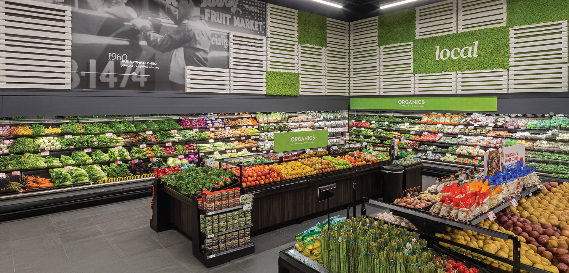 Longo's is a family-operated Canadian grocery chain that began as a fruit market in 1956. The store design features prominent signage for "Organics" and "local" produce. The black and white mural in the background references the company's founding year of 1960.