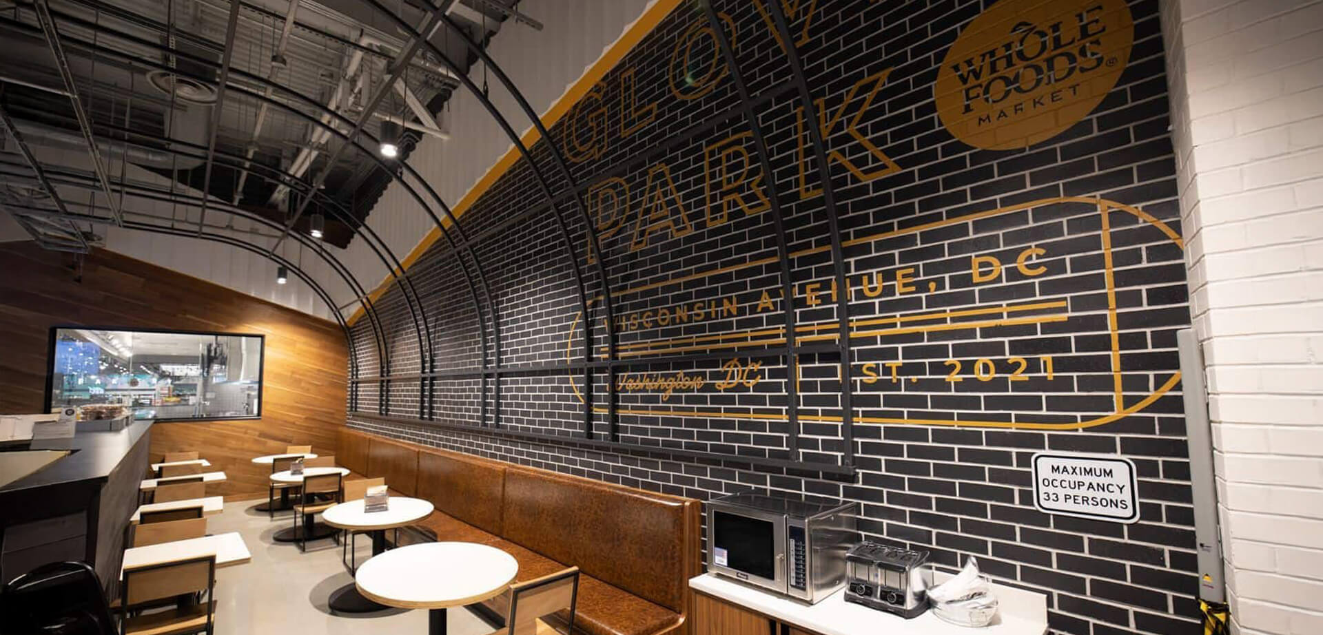 Restaurante Whole Foods Market ubicado en el vecindario Glover Park de Washington, D.C., en 2323 Wisconsin Ave NW. El interior distintivo con la pared de ladrillo negro y el texto amarillo es parte del diseño único de la tienda, que fue el primer Whole Foods en presentar la tecnología de compras sin cajero "Just Walk Out" de Amazon.