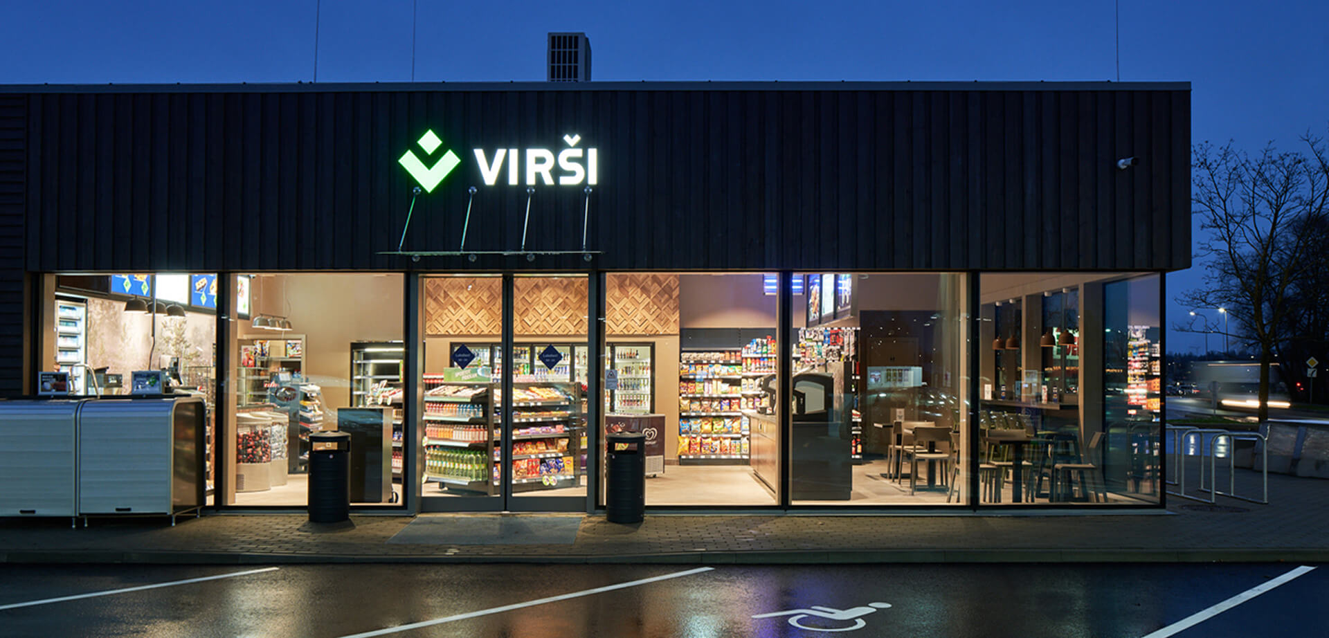 Das Bild zeigt eine Tankstelle von Virši, einem führenden lettischen Händler für Kraftstoffe und alternative Energien, der auch eine Kette von Convenience-Stores betreibt. Convenience-Store: Die Tankstellen verfügen über einen Convenience-Store und ein Café, die oft rund um die Uhr geöffnet sind und eine Auswahl an Produkten wie frische Lebensmittel, Snacks, Kaffee, Getränke und Autozubehör anbieten.