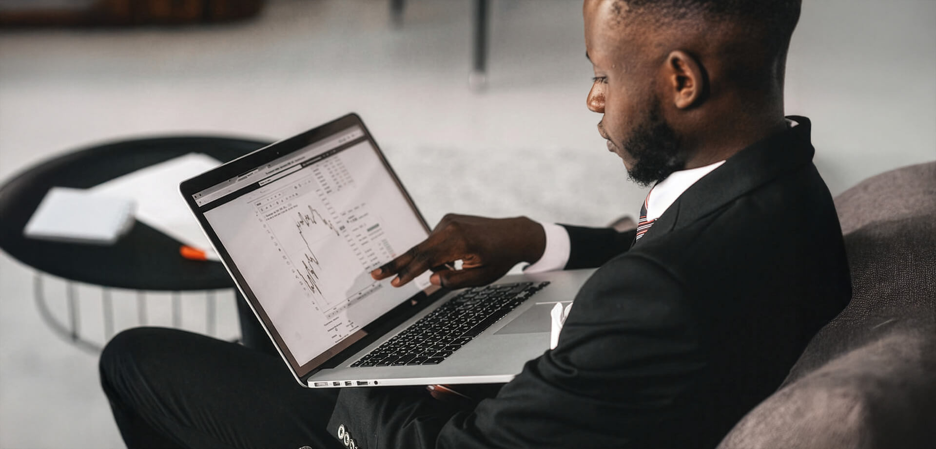 A businessman analyzing financial charts on a Lloyds laptop screen. Financial analysis involves reviewing balance sheets and cash flow statements to assess a company's health.