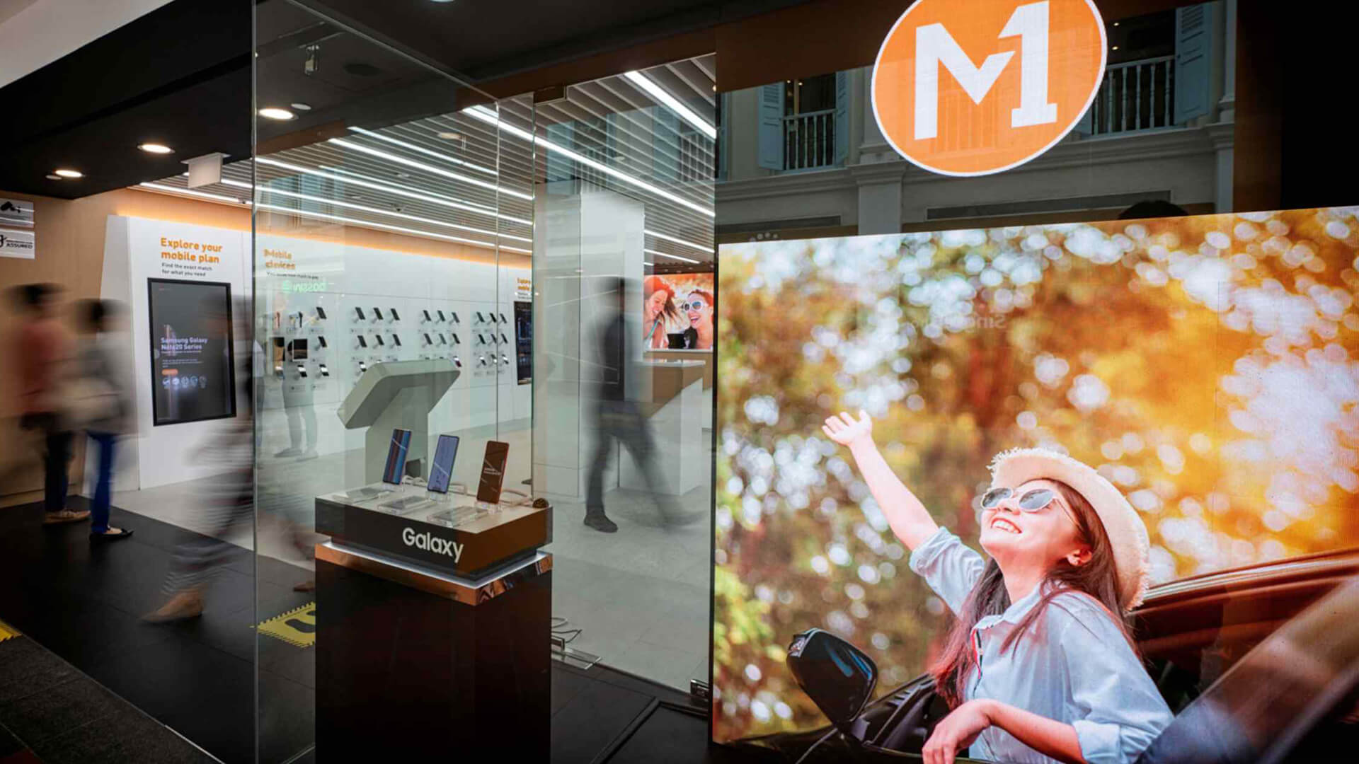This image features an M1 telecommunications storefront, a prominent mobile service provider based in Singapore.